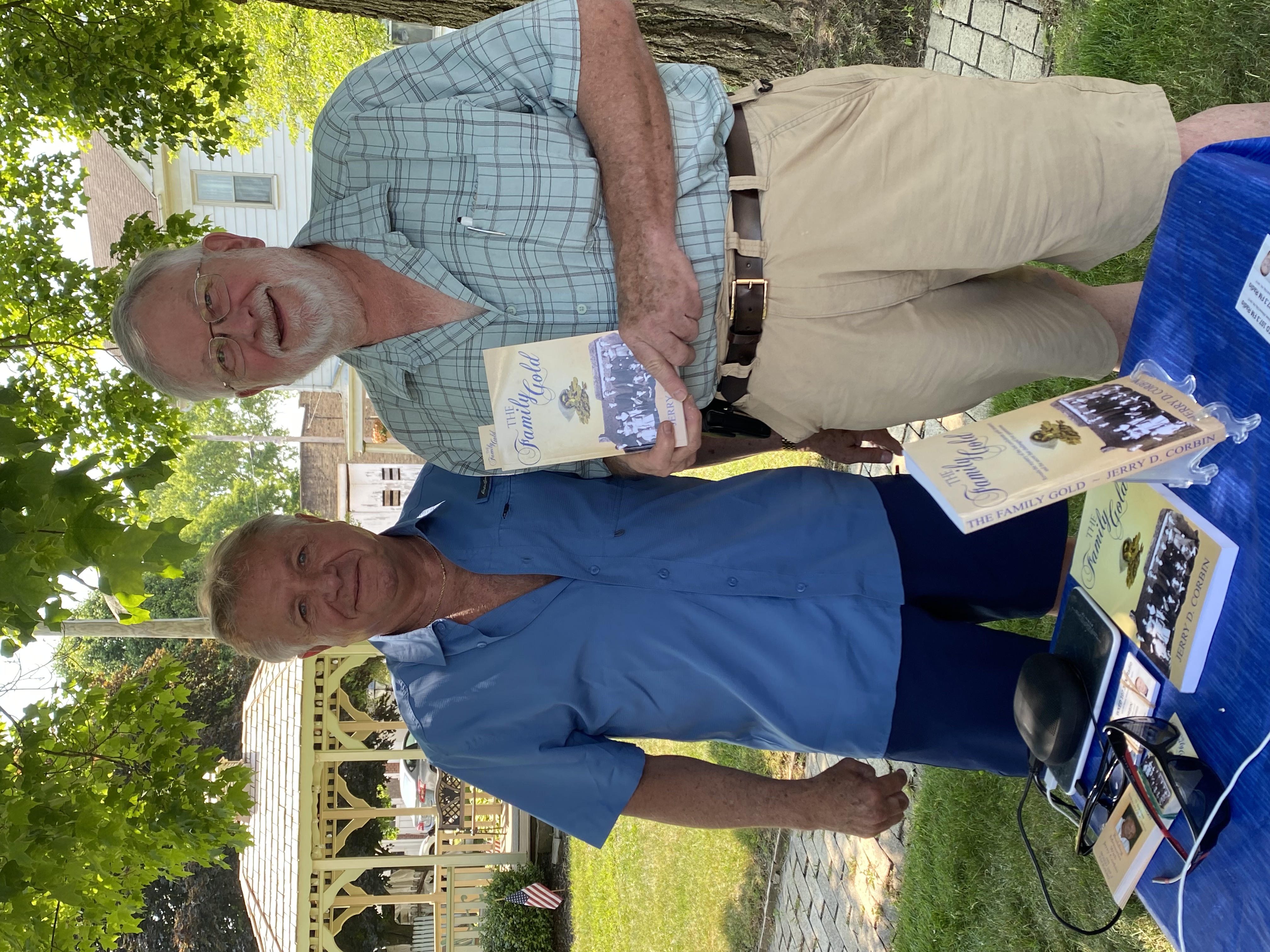 Reader holding The Family Gold by the gazebo